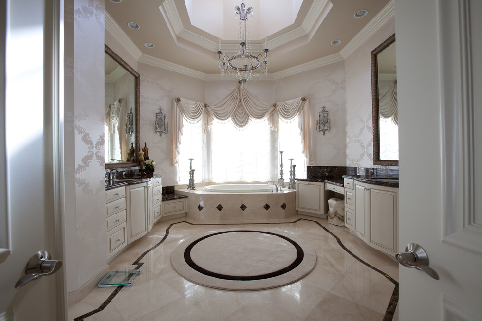 Large traditional master bathroom in Miami with a drop-in tub, recessed-panel cabinets, white cabinets, white walls, travertine floors, an undermount sink and marble benchtops.