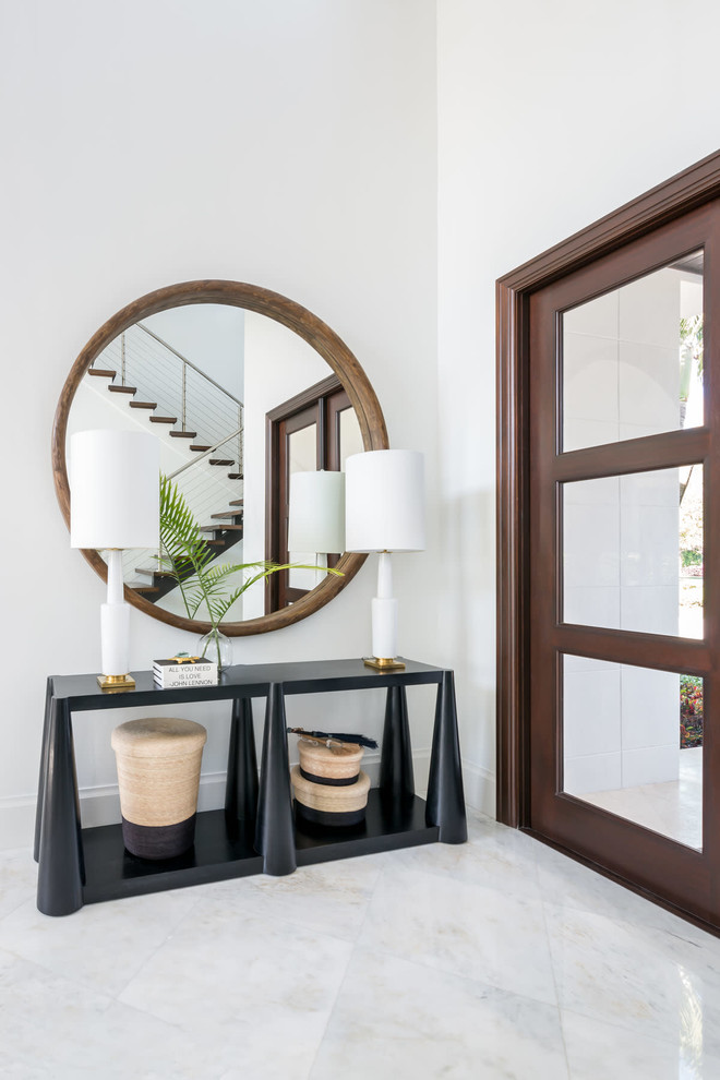 Design ideas for a beach style entryway in Miami with white walls, a glass front door and white floor.