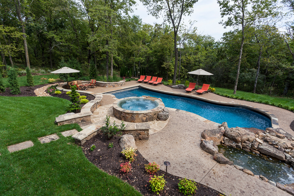 Large arts and crafts backyard custom-shaped pool in Kansas City with a water feature and concrete slab.