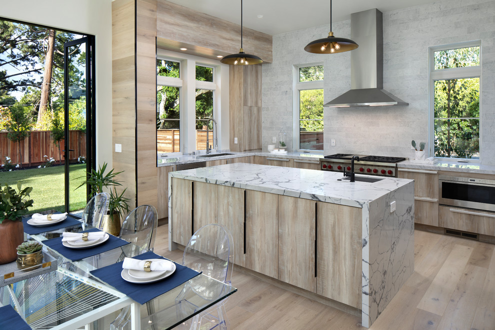 This is an example of a contemporary u-shaped eat-in kitchen in San Francisco with an undermount sink, flat-panel cabinets, light wood cabinets, grey splashback, stainless steel appliances, light hardwood floors, with island, beige floor and white benchtop.