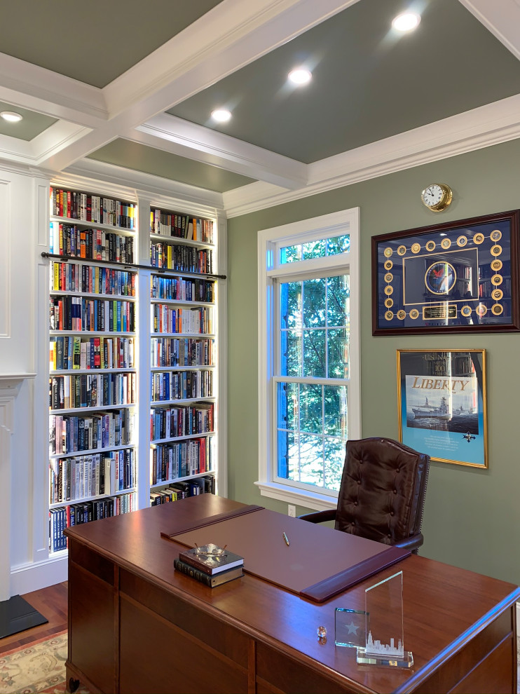 Photo of a mid-sized traditional home office in Philadelphia with a library, green walls, medium hardwood floors, a freestanding desk, orange floor, coffered and panelled walls.