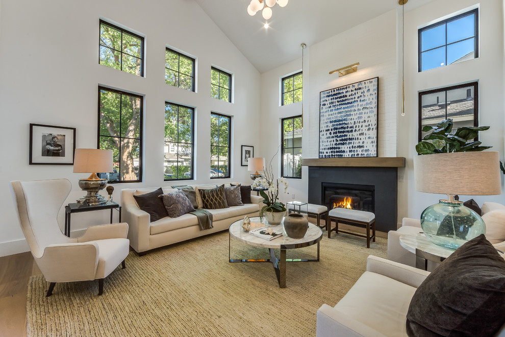 This is an example of a mid-sized transitional open concept living room in Los Angeles with white walls, light hardwood floors, a standard fireplace, brown floor, no tv and a metal fireplace surround.
