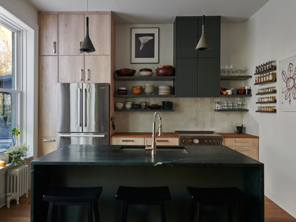 Inspiration for a contemporary galley medium tone wood floor and brown floor kitchen remodel in New York with an undermount sink, flat-panel cabinets, light wood cabinets, wood countertops, beige backsplash, stainless steel appliances, an island and brown countertops