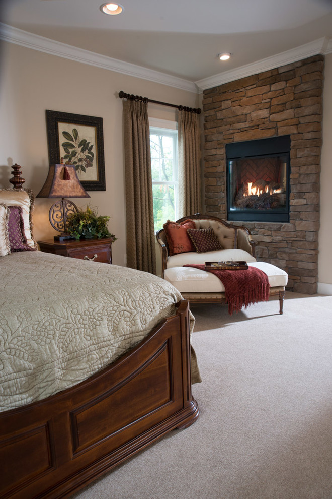 Design ideas for an expansive arts and crafts master bedroom in Other with beige walls, carpet, a two-sided fireplace, a stone fireplace surround and beige floor.
