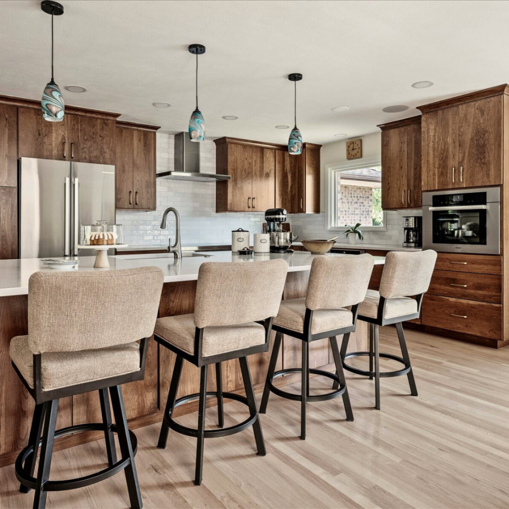 Eat-in kitchen - large transitional l-shaped light wood floor and brown floor eat-in kitchen idea in Denver with an undermount sink, flat-panel cabinets, medium tone wood cabinets, quartzite countertops, white backsplash, ceramic backsplash, stainless steel appliances, an island and white countertops