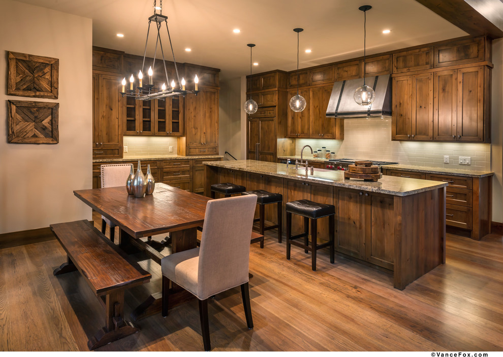 This is an example of a mid-sized transitional l-shaped eat-in kitchen in Sacramento with a farmhouse sink, shaker cabinets, medium wood cabinets, granite benchtops, beige splashback, subway tile splashback, panelled appliances, medium hardwood floors and with island.