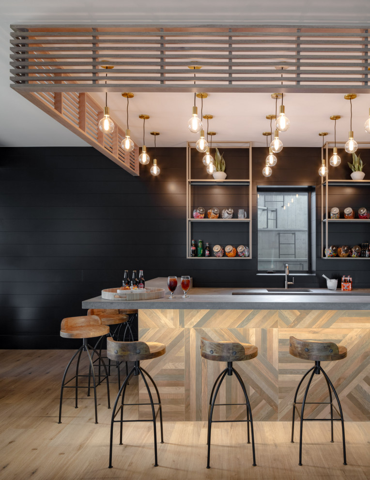 Transitional l-shaped light wood floor and beige floor seated home bar photo in Denver with an undermount sink, black backsplash, shiplap backsplash, gray countertops, floating shelves and concrete countertops