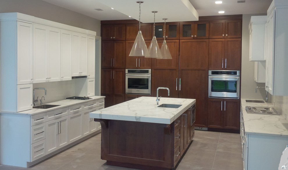 Inspiration for a large transitional u-shaped separate kitchen in New York with an undermount sink, beaded inset cabinets, white cabinets, marble benchtops, white splashback, stainless steel appliances, porcelain floors, with island and brown floor.
