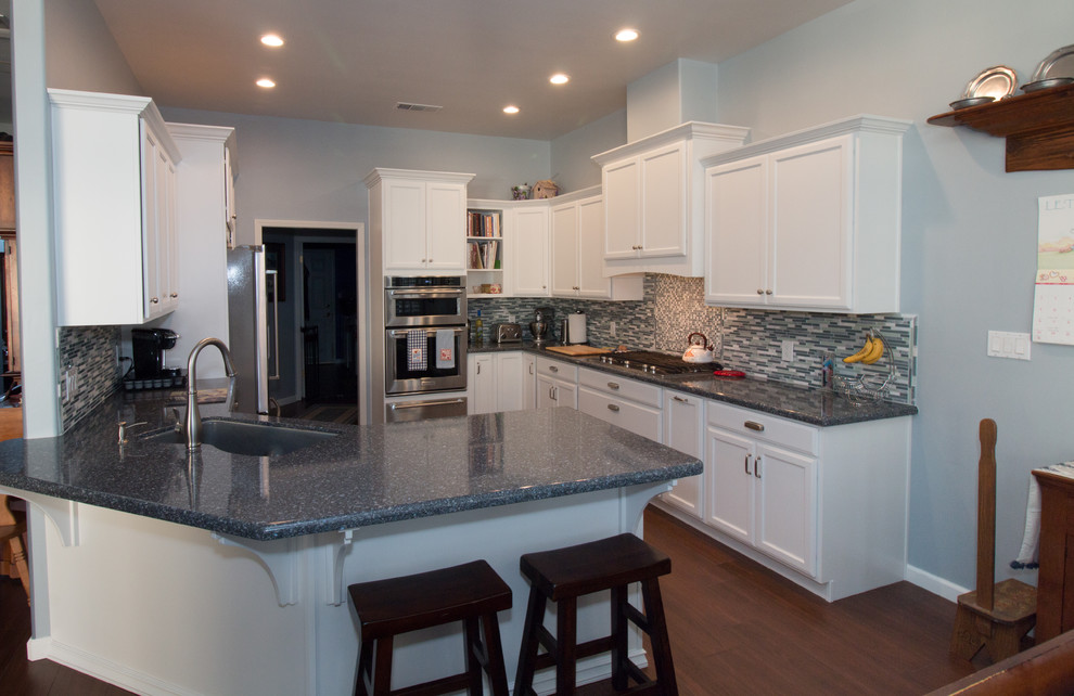 Inspiration for a mid-sized transitional u-shaped porcelain tile and brown floor open concept kitchen remodel with an undermount sink, recessed-panel cabinets, white cabinets, quartz countertops, blue backsplash, mosaic tile backsplash, stainless steel appliances and blue countertops
