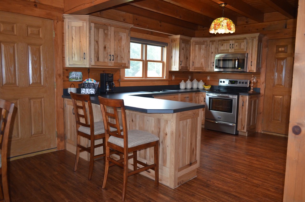Inspiration for a mid-sized rustic u-shaped dark wood floor and brown floor eat-in kitchen remodel with a drop-in sink, recessed-panel cabinets, light wood cabinets, solid surface countertops, stainless steel appliances and a peninsula