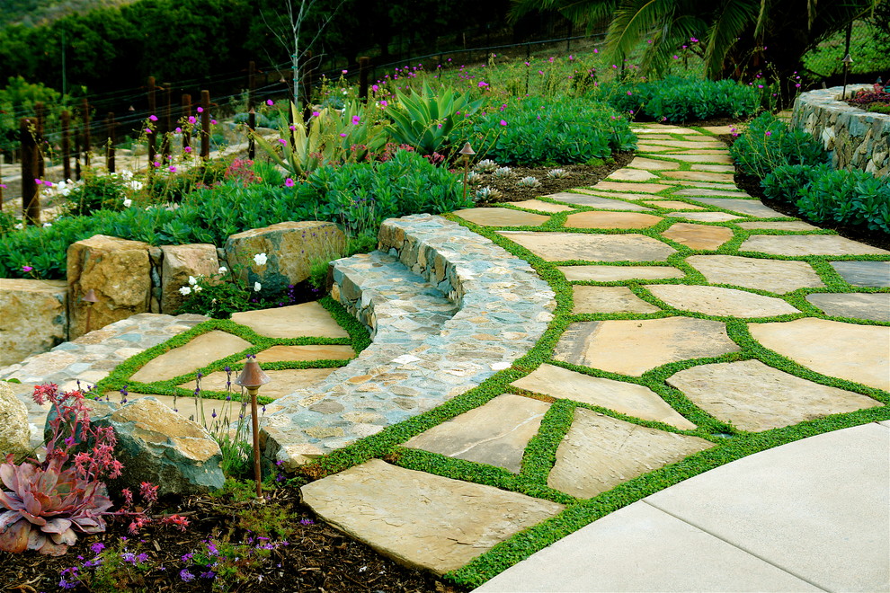 Photo of a mediterranean sloped garden in San Diego with natural stone pavers.