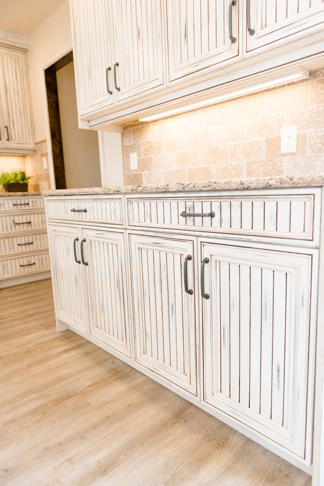 Large transitional u-shaped light wood floor and brown floor eat-in kitchen photo in Oklahoma City with louvered cabinets, distressed cabinets, marble countertops, multicolored backsplash, stone tile backsplash, white appliances, a peninsula and an undermount sink