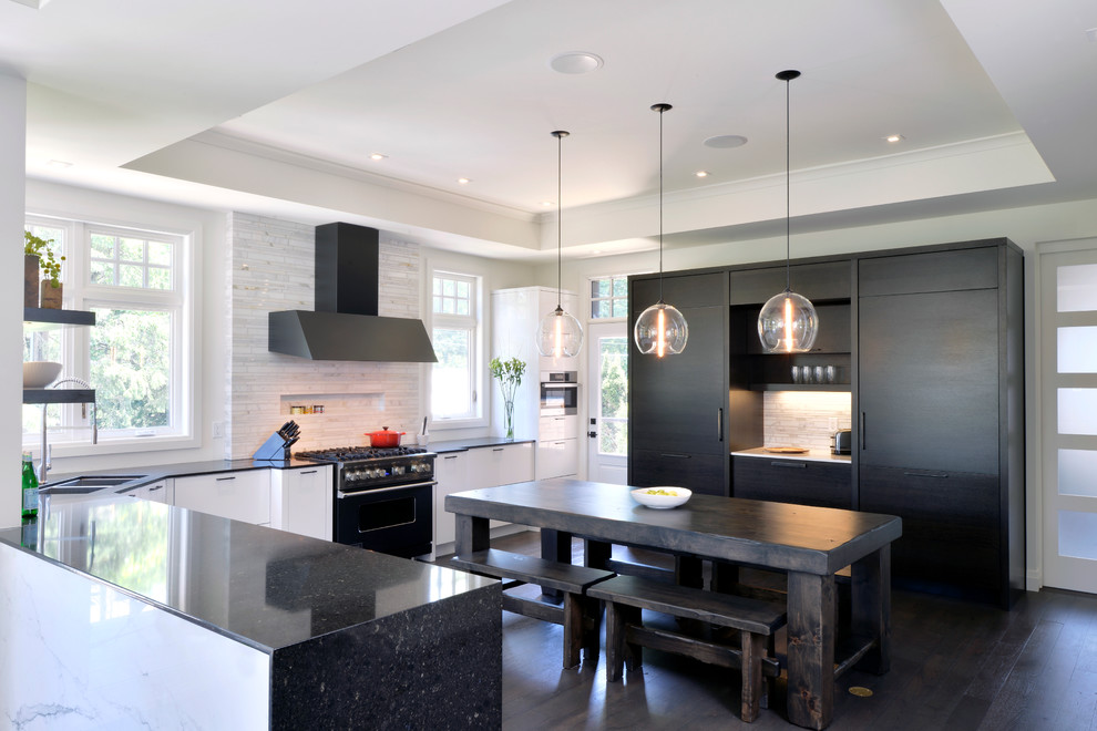 Design ideas for a large transitional u-shaped eat-in kitchen in Toronto with an undermount sink, flat-panel cabinets, recycled glass benchtops, white splashback, panelled appliances, with island, white cabinets and dark hardwood floors.