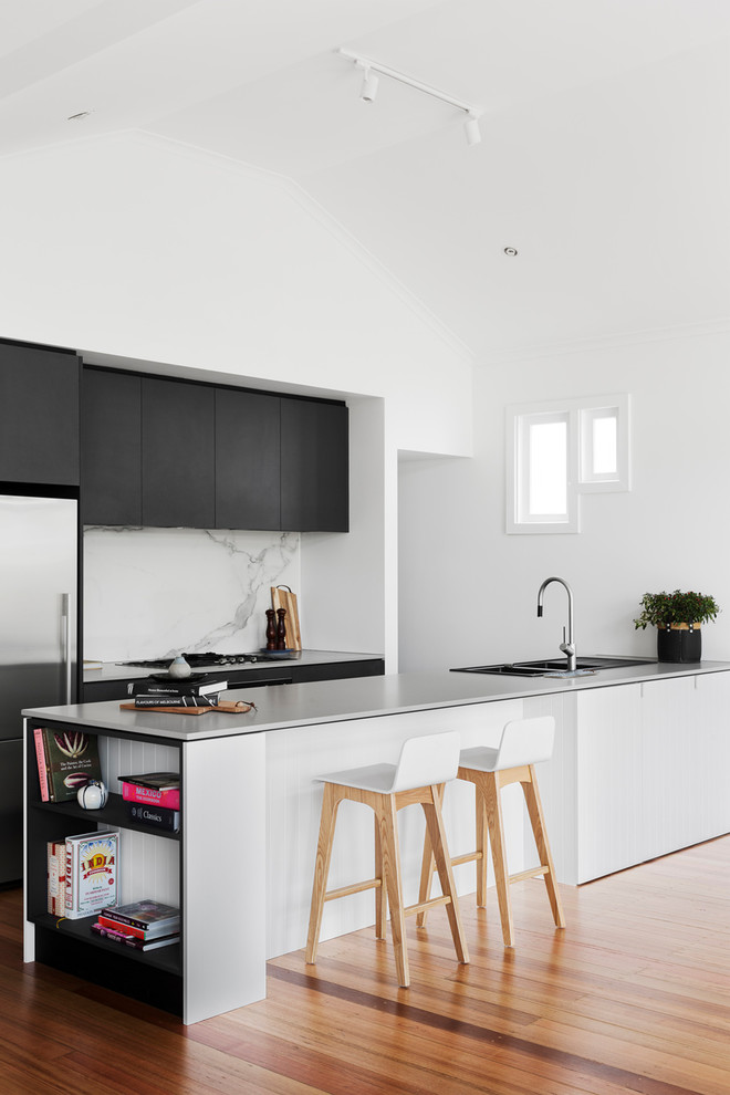 Inspiration for a contemporary galley open plan kitchen in Melbourne with an integrated sink, flat-panel cabinets, black cabinets, concrete benchtops, white splashback, marble splashback, stainless steel appliances, medium hardwood floors and a peninsula.