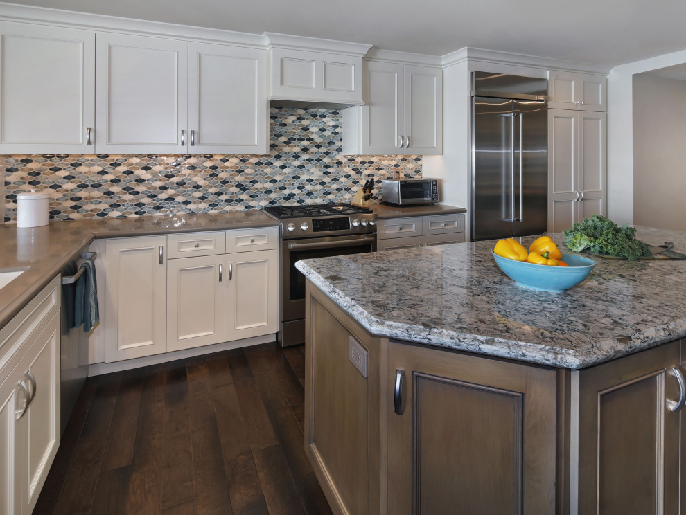 Inspiration for a mid-sized transitional l-shaped kitchen in Orange County with an undermount sink, raised-panel cabinets, white cabinets, quartz benchtops, multi-coloured splashback, ceramic splashback, stainless steel appliances, dark hardwood floors, with island, brown floor and beige benchtop.