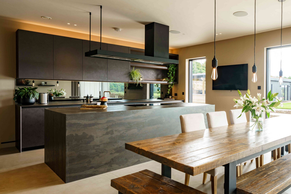 Design ideas for a large contemporary l-shaped eat-in kitchen in Cardiff with flat-panel cabinets, mirror splashback, black appliances and with island.
