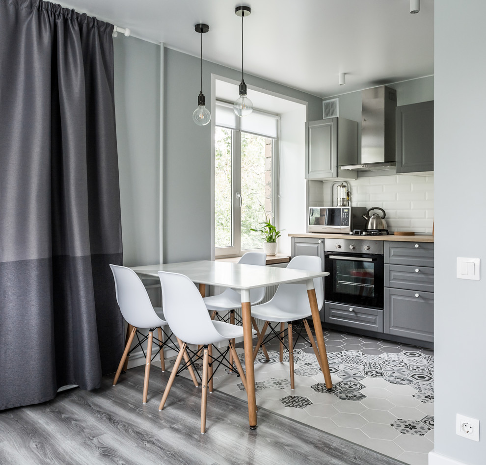 Contemporary single-wall open plan kitchen in Moscow with raised-panel cabinets, grey cabinets, white splashback, subway tile splashback, stainless steel appliances, no island and grey floor.