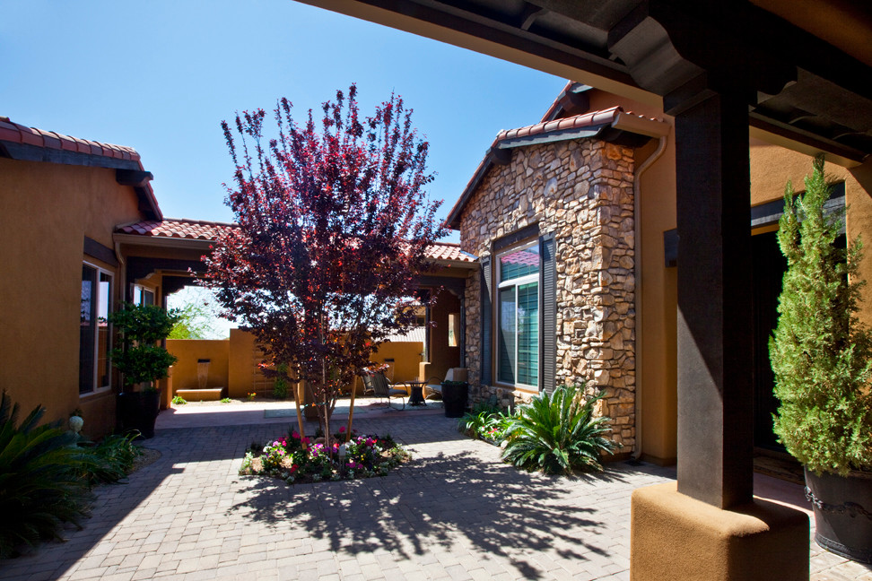Example of a large mountain style backyard brick patio design in Phoenix with a roof extension