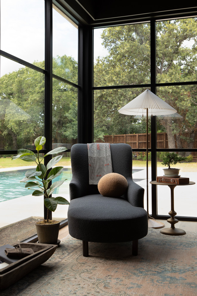 Hill Country Modern Meets Southlake, Texas - This Hill Country Modern home in Southlake combines modern design with comfort, featuring light-filled spaces and unique details reflecting the family's eclectic style for play and sophistication. 

This lounge features a floor-to-ceiling corner window with panoramic views. The dark palette is complemented by cozy furniture and statement lighting, creating an inviting and sophisticated atmosphere.
