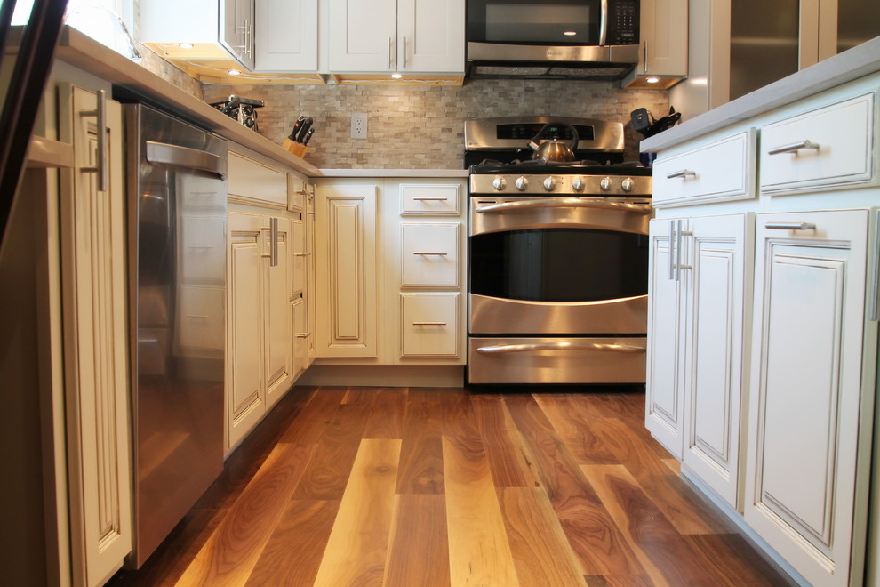 Eat-in kitchen - large transitional l-shaped medium tone wood floor eat-in kitchen idea in Denver with an undermount sink, shaker cabinets, gray cabinets, quartz countertops, gray backsplash, stone tile backsplash, stainless steel appliances and an island