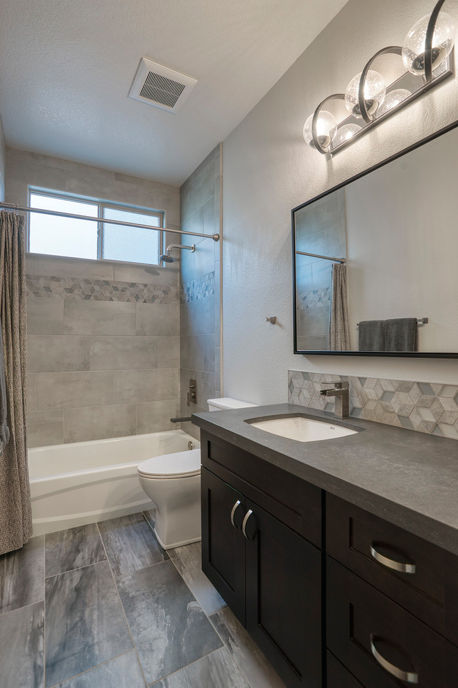 Photo of a mid-sized modern kids bathroom with shaker cabinets, brown cabinets, a shower/bathtub combo, a one-piece toilet, multi-coloured tile, grey walls, an undermount sink, a shower curtain and grey benchtops.
