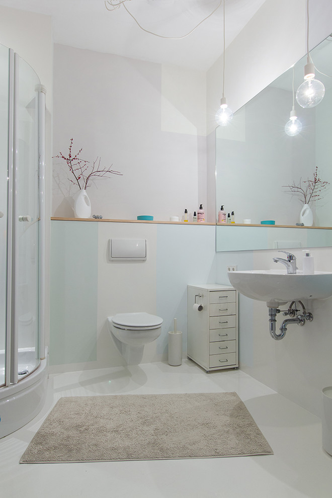 Photo of a small contemporary 3/4 bathroom in Berlin with a wall-mount sink, a corner shower, a wall-mount toilet, white walls, flat-panel cabinets, white cabinets, ceramic floors, white floor and a hinged shower door.