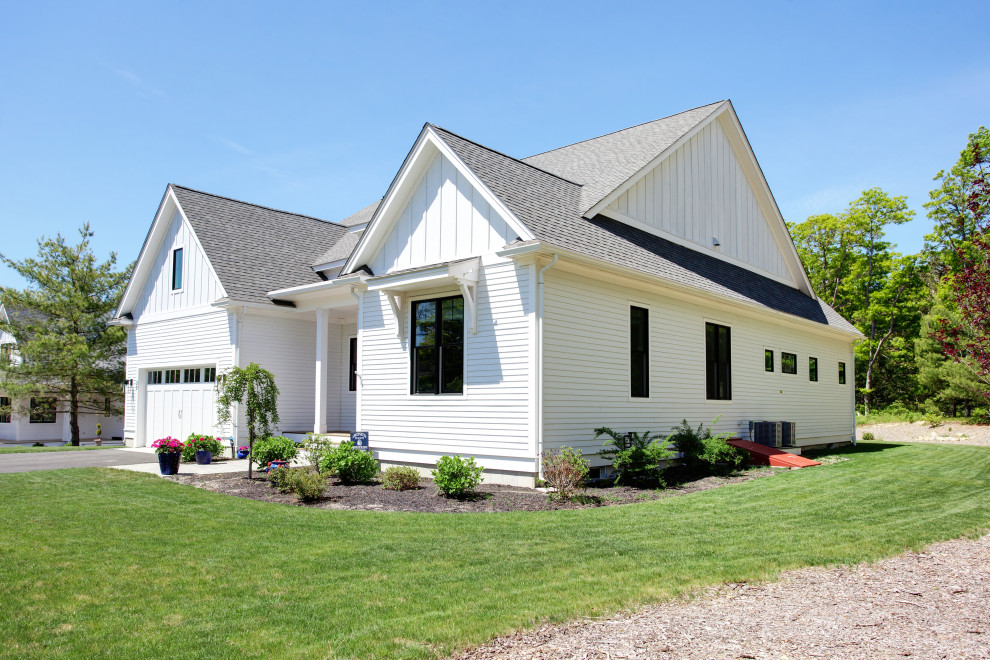 Idée de décoration pour une façade de maison blanche champêtre en bardage à clin de taille moyenne et de plain-pied avec un revêtement en vinyle, un toit à deux pans, un toit en shingle et un toit gris.