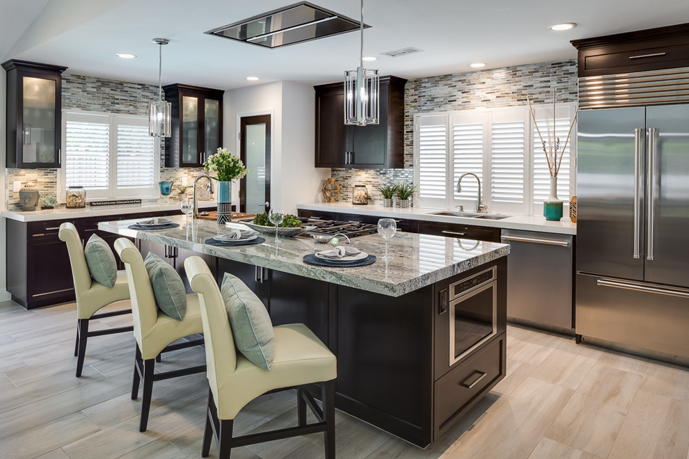 Open concept kitchen - mid-sized transitional l-shaped porcelain tile open concept kitchen idea in San Diego with an undermount sink, recessed-panel cabinets, dark wood cabinets, quartzite countertops, brown backsplash, matchstick tile backsplash, stainless steel appliances and an island