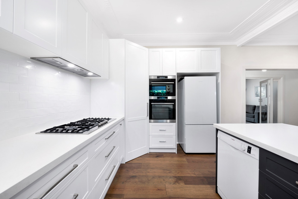 Mittelgroße Moderne Küche in U-Form mit Vorratsschrank, Schrankfronten im Shaker-Stil, weißen Schränken, Küchenrückwand in Weiß, Rückwand aus Keramikfliesen, Halbinsel und weißer Arbeitsplatte in Sydney