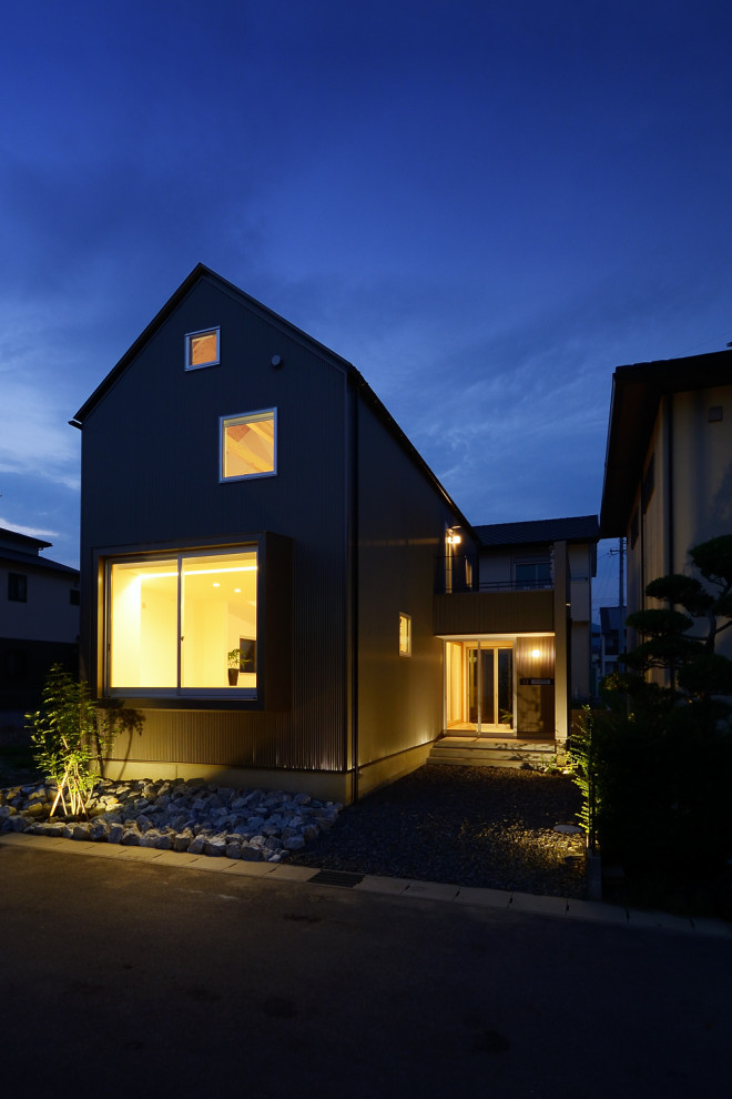 Réalisation d'une façade de maison métallique et verte nordique en planches et couvre-joints de taille moyenne et à un étage avec un toit à deux pans, un toit en métal et un toit gris.