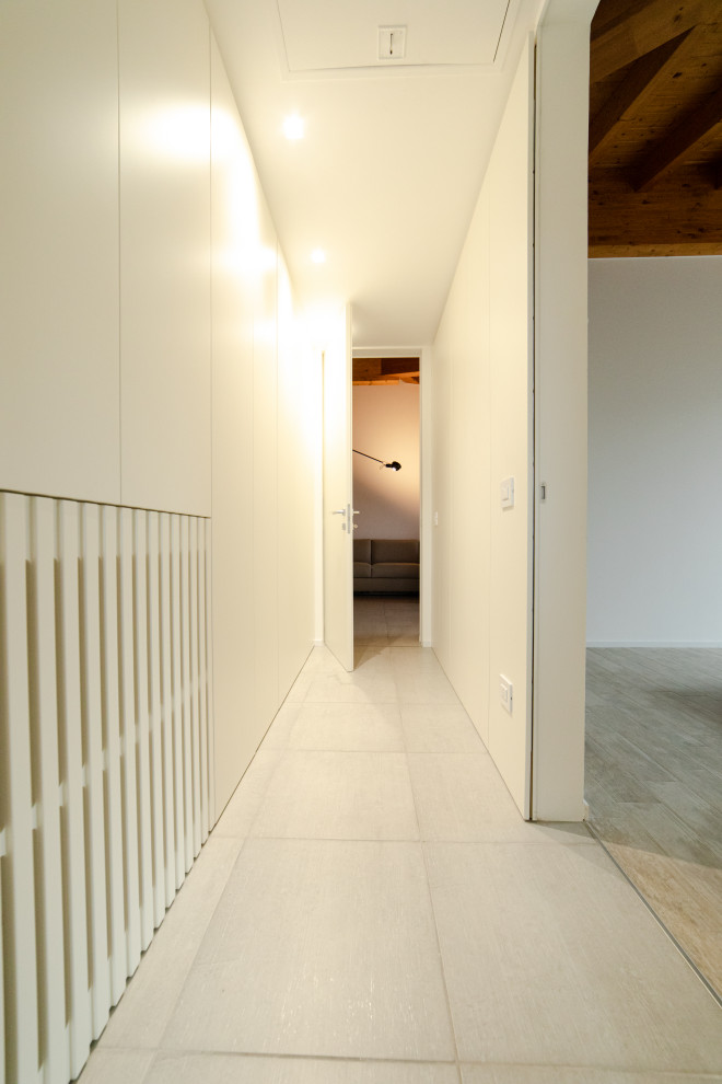 Hallway - mid-sized modern porcelain tile, gray floor, tray ceiling and wainscoting hallway idea in Milan with white walls