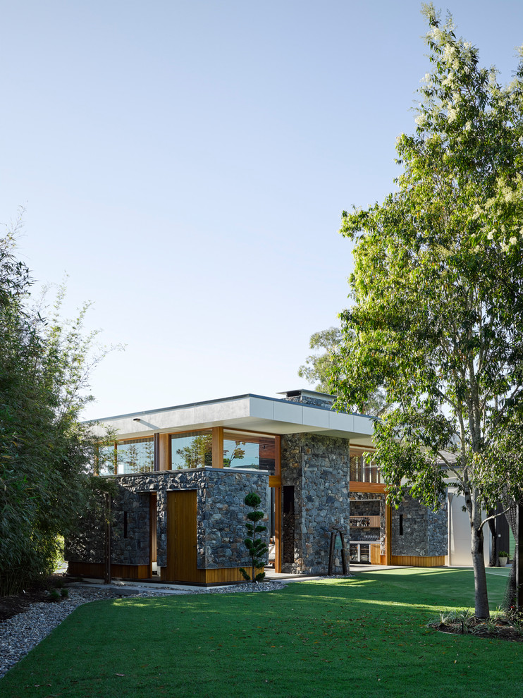 Photo of a modern one-storey grey exterior in Brisbane with stone veneer and a flat roof.