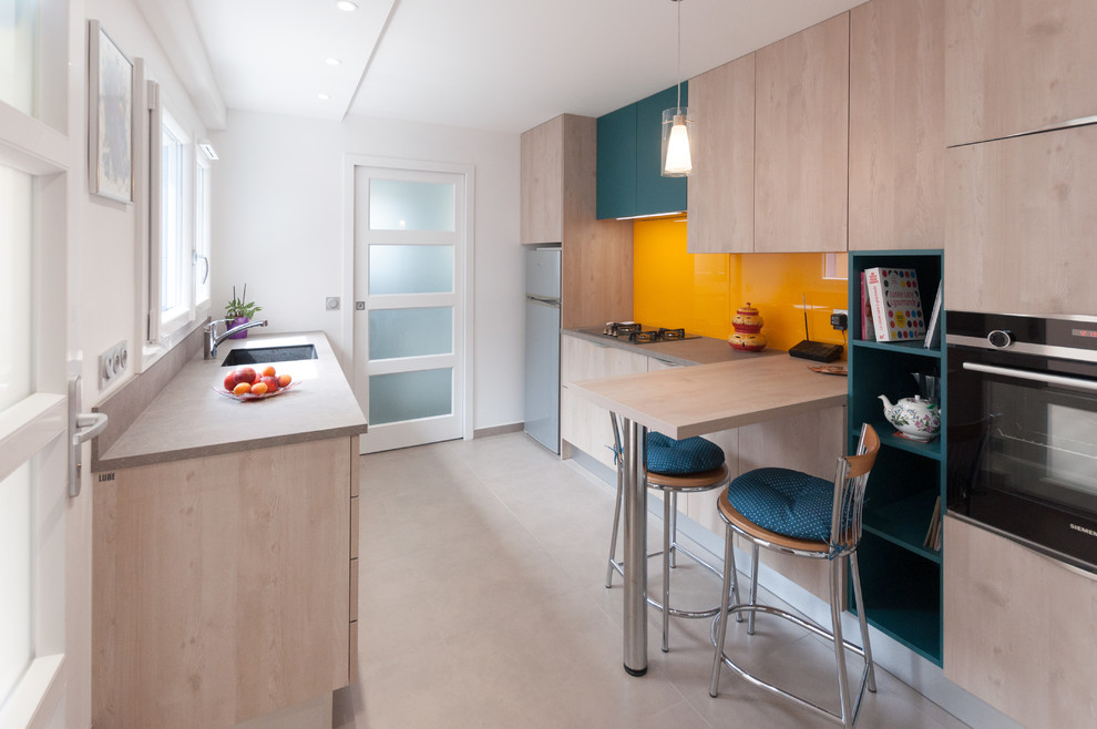 Inspiration for a mid-sized contemporary galley separate kitchen in Lyon with an integrated sink, beaded inset cabinets, light wood cabinets, laminate benchtops, orange splashback, glass sheet splashback, stainless steel appliances, ceramic floors, no island, grey floor and grey benchtop.
