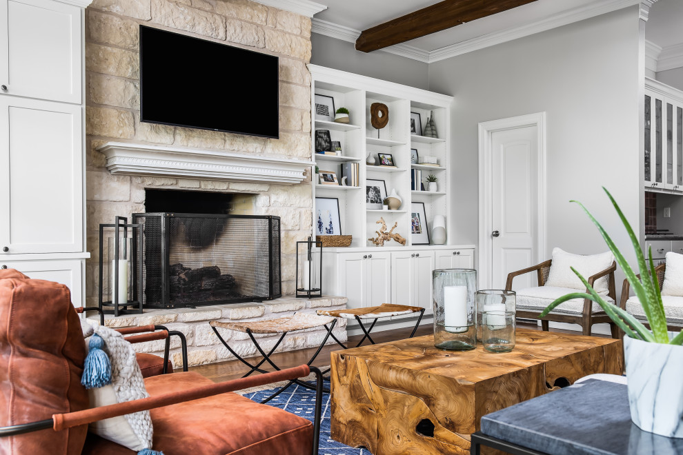 Transitional enclosed living room in Austin with grey walls, medium hardwood floors, a standard fireplace, a stone fireplace surround, a wall-mounted tv, brown floor and exposed beam.