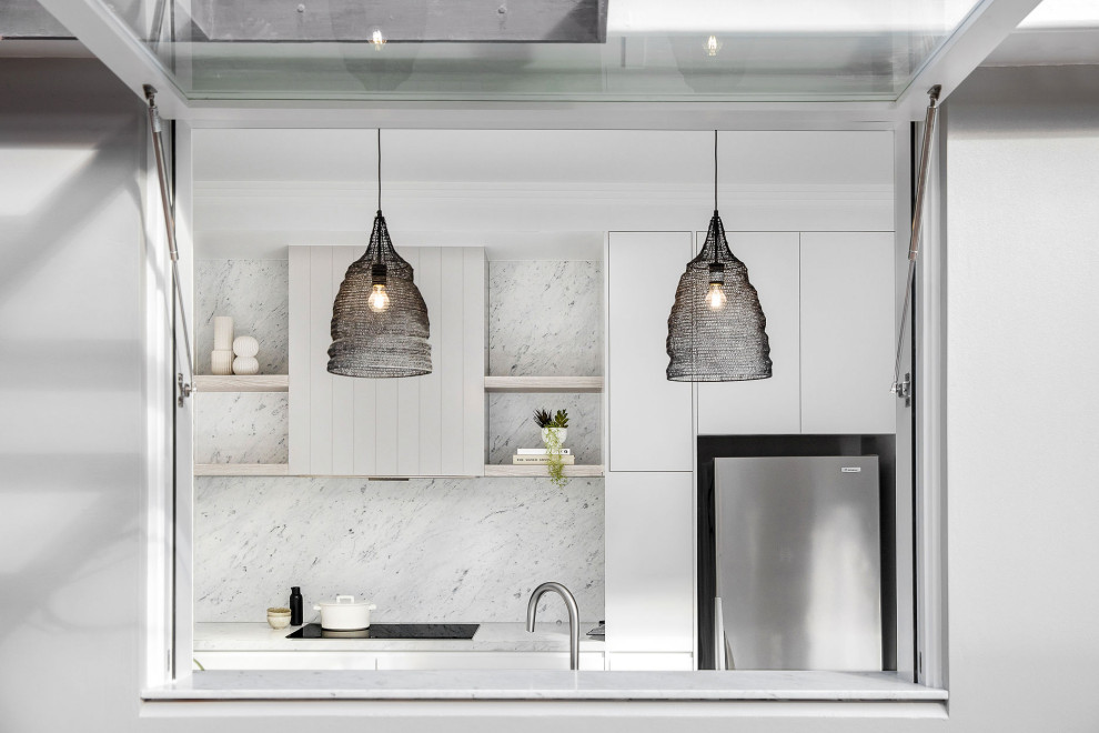 Inspiration for a mid-sized beach style u-shaped eat-in kitchen in Sydney with an undermount sink, flat-panel cabinets, white cabinets, marble benchtops, grey splashback, marble splashback, stainless steel appliances, medium hardwood floors, no island, brown floor and grey benchtop.
