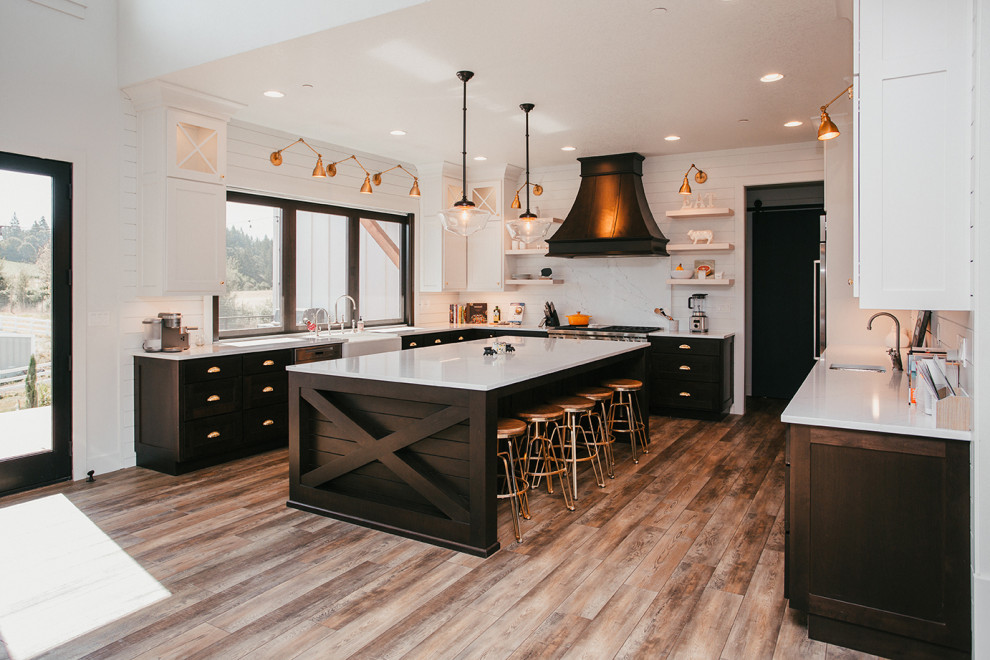 This is an example of an expansive country u-shaped kitchen in Portland with a farmhouse sink, shaker cabinets, dark wood cabinets, quartz benchtops, white splashback, shiplap splashback, medium hardwood floors, with island and brown floor.