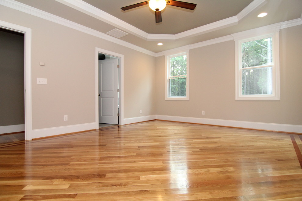 This is an example of a large contemporary master bedroom in Raleigh with grey walls and light hardwood floors.