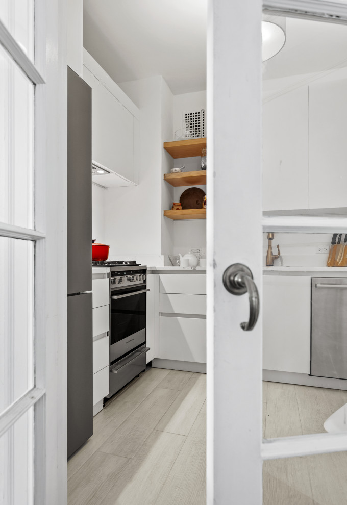 Mid-sized transitional l-shaped light wood floor and white floor enclosed kitchen photo in Chicago with an undermount sink, flat-panel cabinets, white cabinets, marble countertops, white backsplash, subway tile backsplash, stainless steel appliances, no island and white countertops