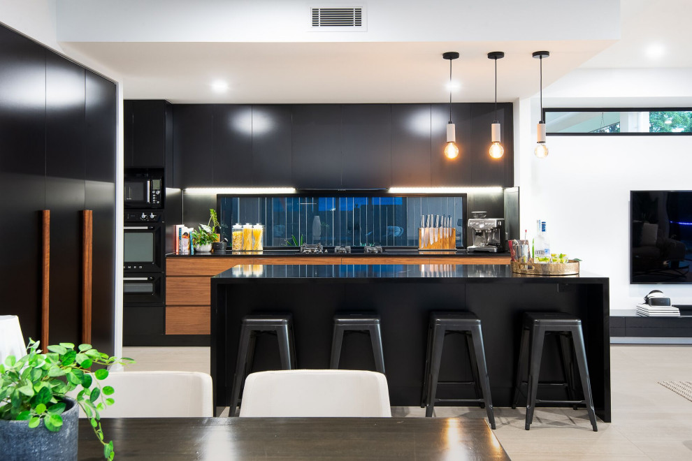 This is an example of a contemporary galley kitchen in Brisbane with flat-panel cabinets, black cabinets, window splashback, with island, grey floor and black benchtop.
