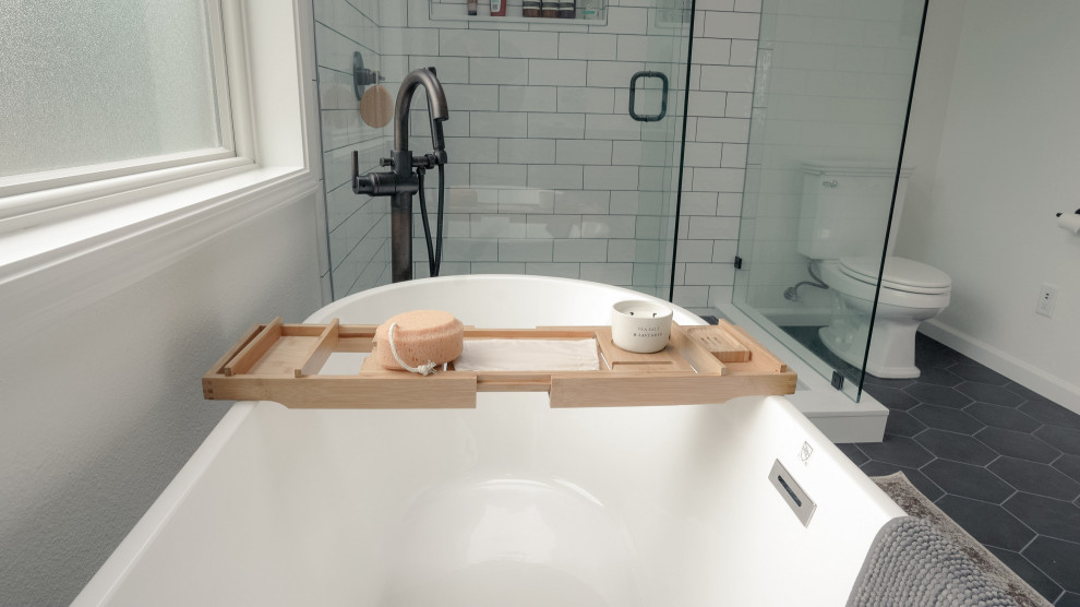 This is an example of a small traditional master bathroom in Seattle with beaded inset cabinets, white cabinets, a freestanding tub, an alcove shower, a one-piece toilet, white tile, ceramic tile, white walls, cement tiles, an undermount sink, marble benchtops, black floor, a hinged shower door, white benchtops, an enclosed toilet, a single vanity, a freestanding vanity, coffered and wallpaper.