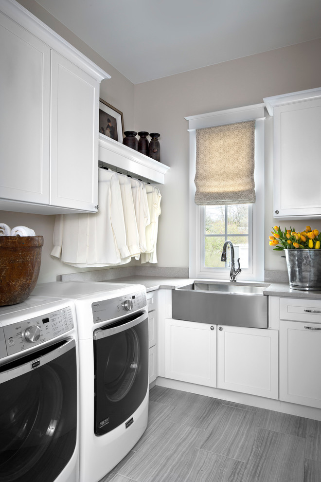 Photo of a transitional l-shaped dedicated laundry room in Other with a farmhouse sink, white cabinets, beige walls and a side-by-side washer and dryer.