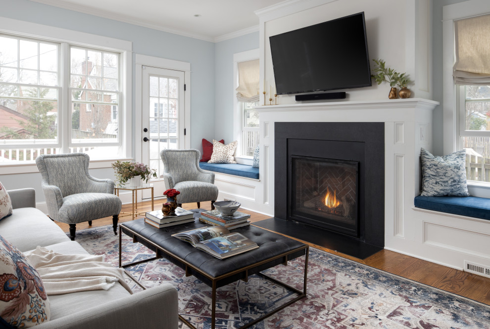 Photo of a traditional open concept family room in DC Metro with blue walls, medium hardwood floors, a standard fireplace, a wall-mounted tv and brown floor.