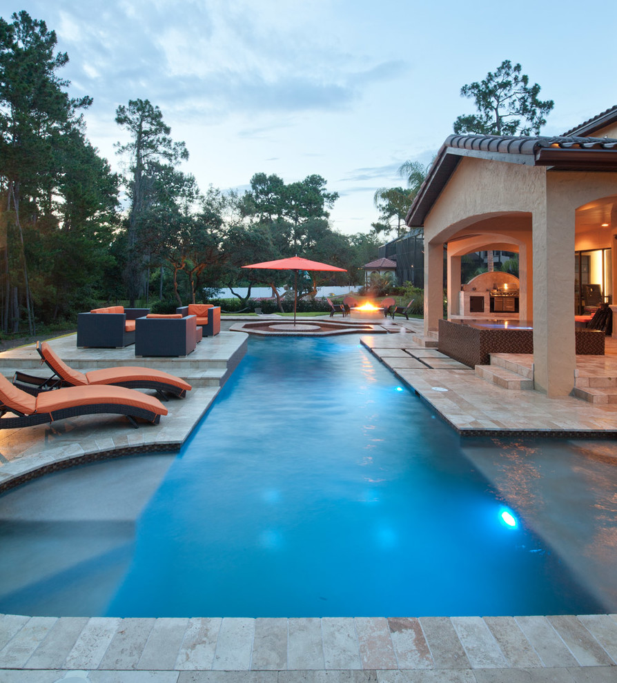 Photo of a mid-sized tropical backyard rectangular lap pool in Orlando with natural stone pavers and a hot tub.