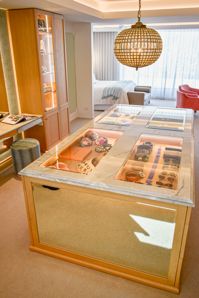 Modern inredning av ett stort omklädningsrum, med luckor med glaspanel, skåp i ljust trä och heltäckningsmatta