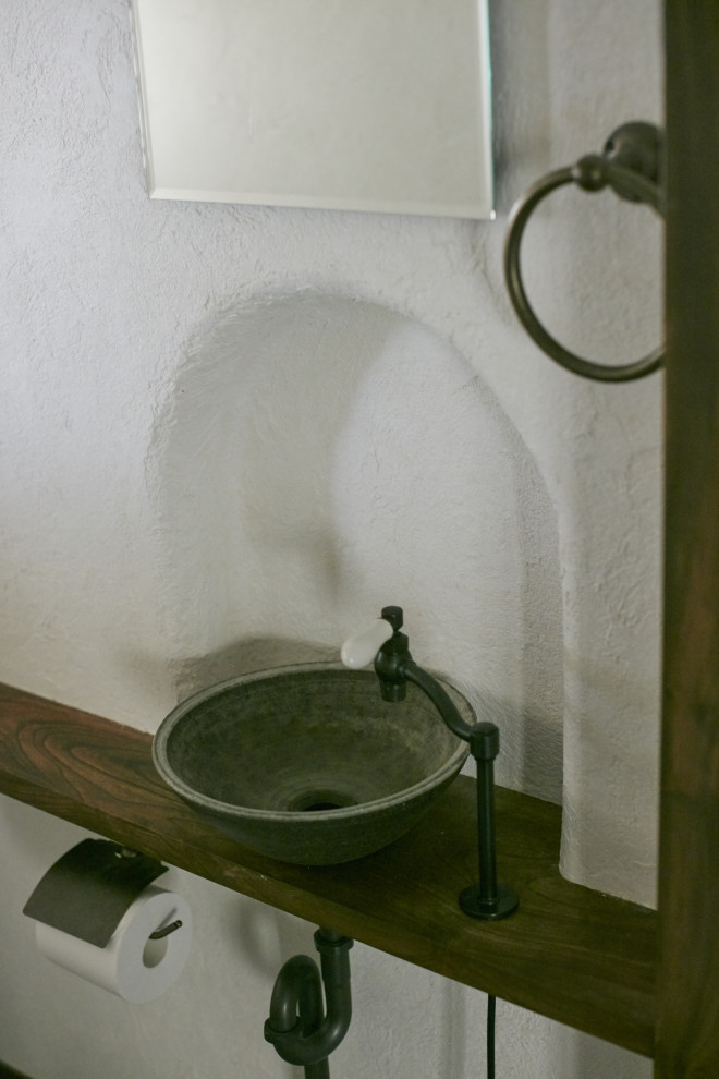 Réalisation d'un petit WC et toilettes avec un carrelage blanc, un mur blanc, sol en béton ciré, une vasque, un plan de toilette marron et meuble-lavabo encastré.