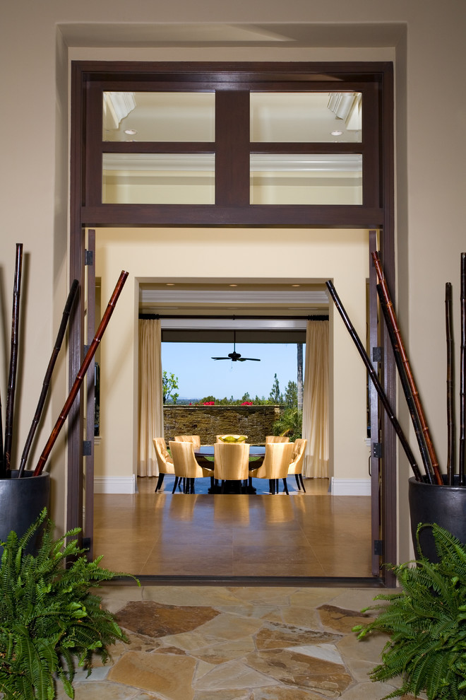 Design ideas for a large tropical front door in Orange County with a double front door, a dark wood front door, beige walls and travertine floors.