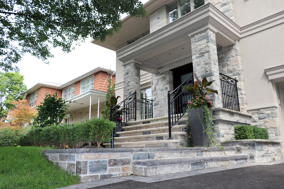 Photo of a mid-sized traditional front yard driveway in Toronto with a retaining wall and natural stone pavers.
