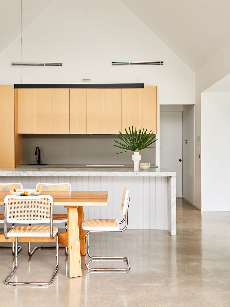 Photo of a mid-sized tropical galley eat-in kitchen in Geelong with a drop-in sink, light wood cabinets, quartz benchtops, grey splashback, engineered quartz splashback, concrete floors, with island, grey floor, white benchtop and vaulted.