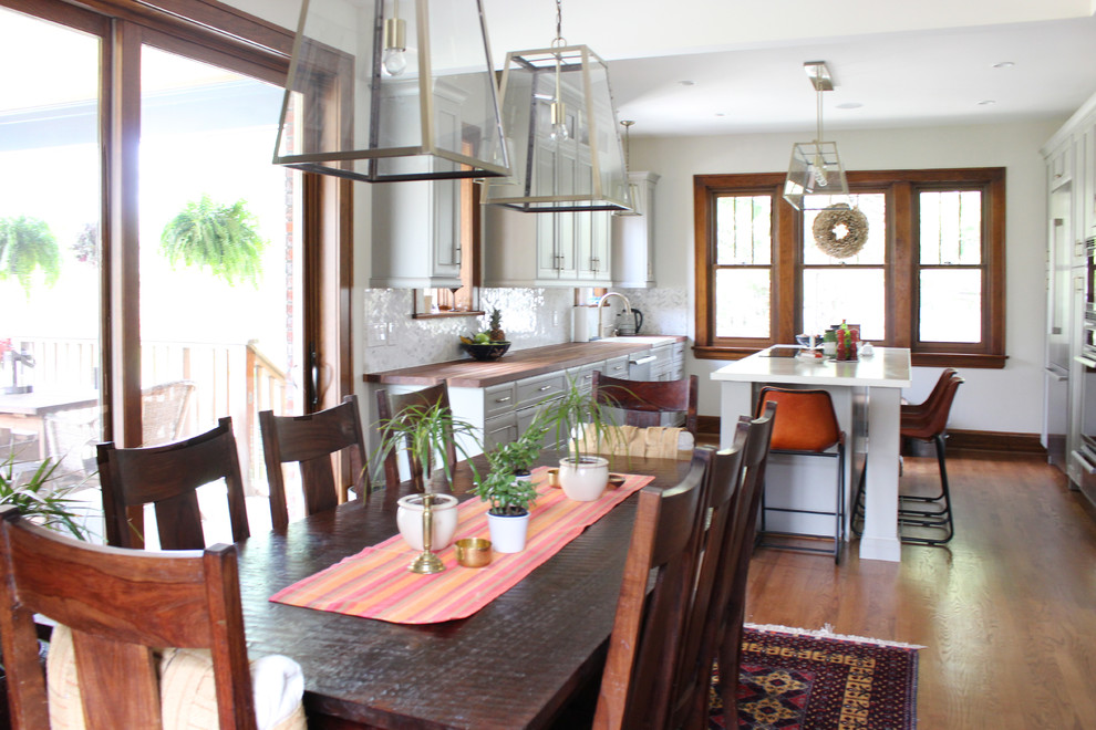 Example of a mid-sized transitional medium tone wood floor eat-in kitchen design with a drop-in sink, gray cabinets, concrete countertops, white backsplash, stainless steel appliances and an island