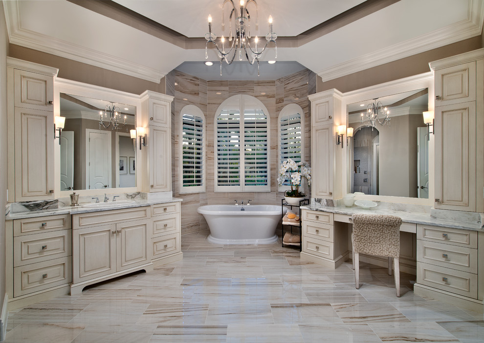 Inspiration for a large traditional master bathroom in Miami with recessed-panel cabinets, beige cabinets, a freestanding tub, brown walls, a drop-in sink and multi-coloured floor.